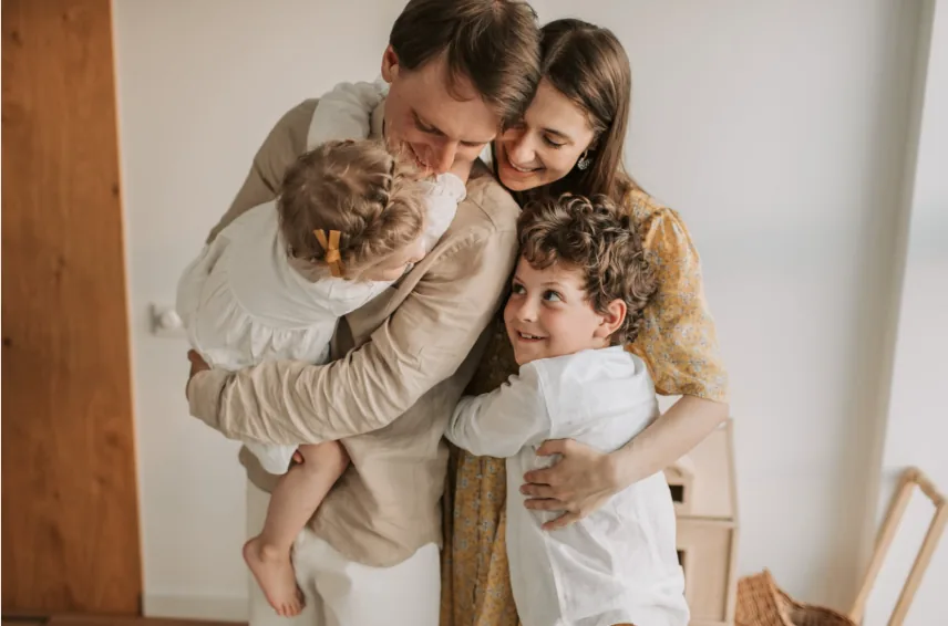 Familie mit zwei Kindern in einer liebevollen Alltagssituation